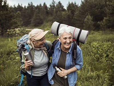 Close up of two senior female friends hiking together.